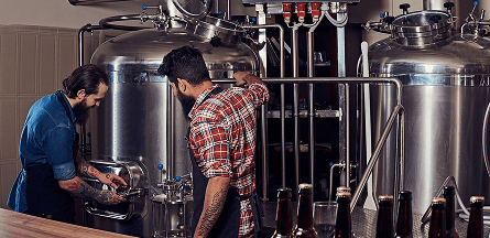 Forio Beer Game - Two male bearded brewmasters work in a brewery